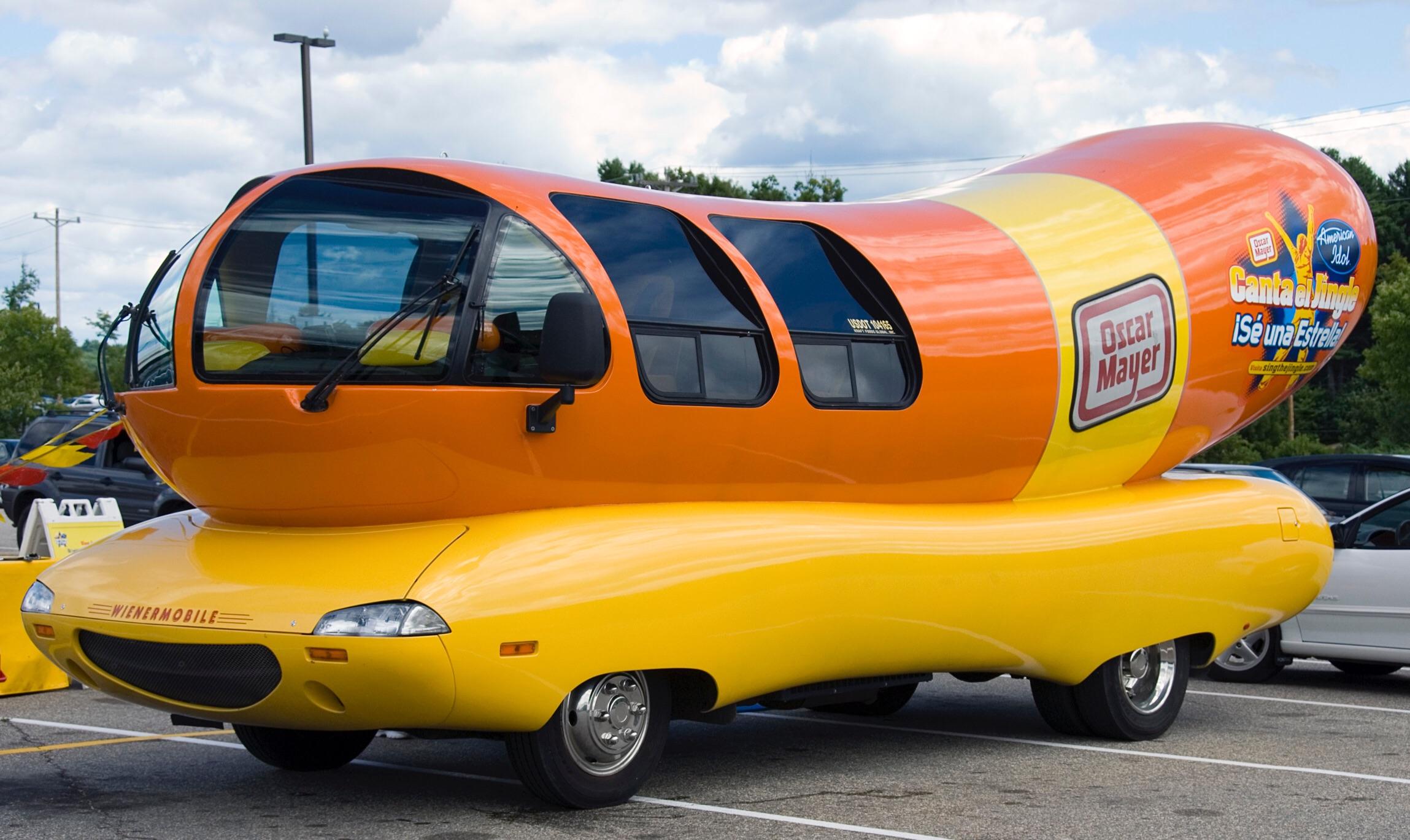 An oversized novelty vehicle shaped like a hot dog, parked in a lot